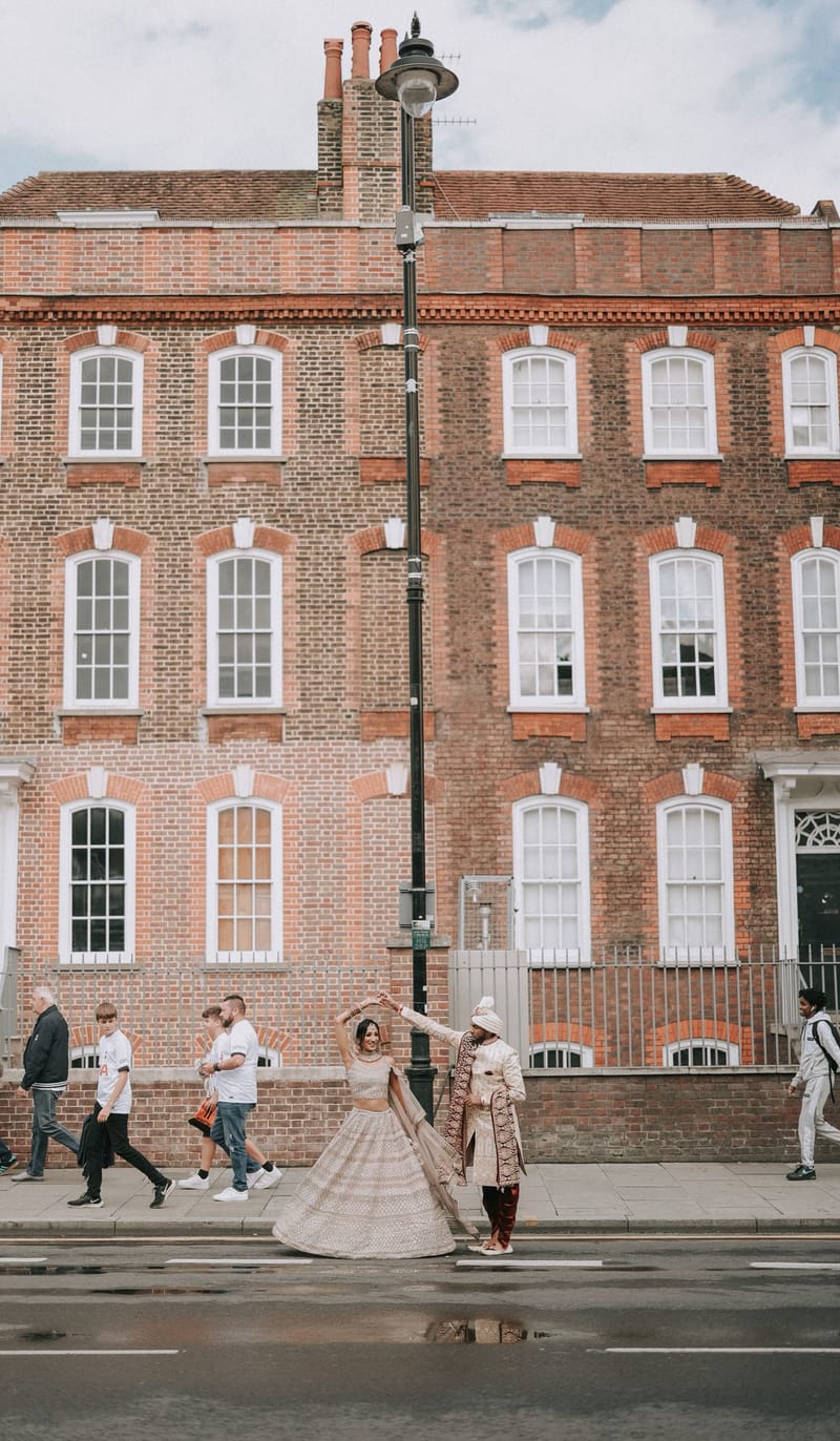 Couple dancing on a London street outside a red-brick Georgian building as people walk past