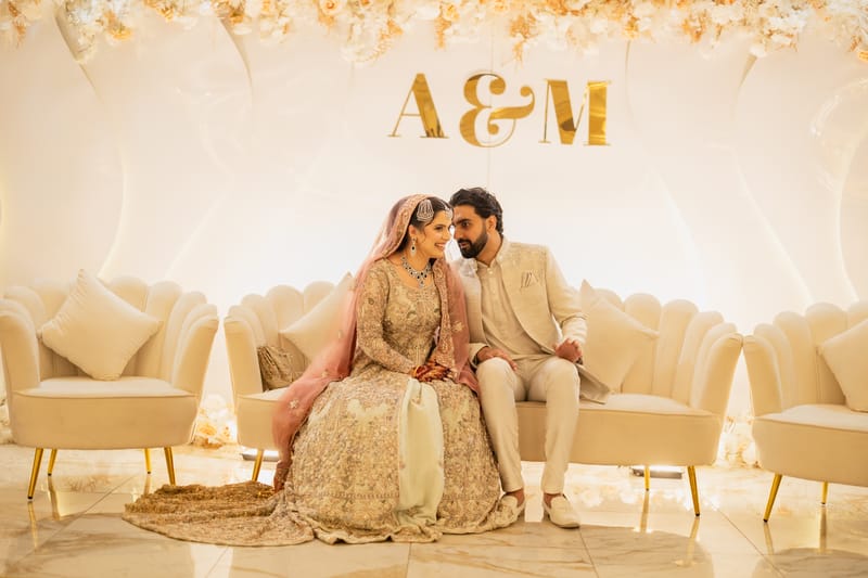 Couple sharing a quiet moment on an ivory stage beneath their gold initials